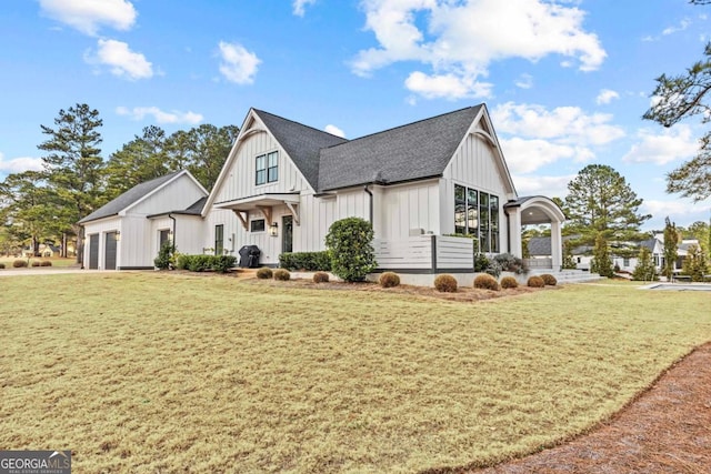 view of front facade featuring a garage, a shingled roof, board and batten siding, and a front yard