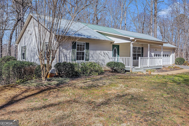 single story home with a garage, metal roof, a porch, and a front yard