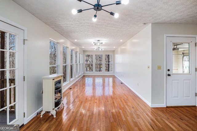 unfurnished room featuring baseboards, plenty of natural light, a textured ceiling, and light wood finished floors