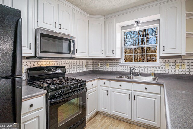 kitchen featuring dark countertops, black appliances, white cabinetry, and a sink