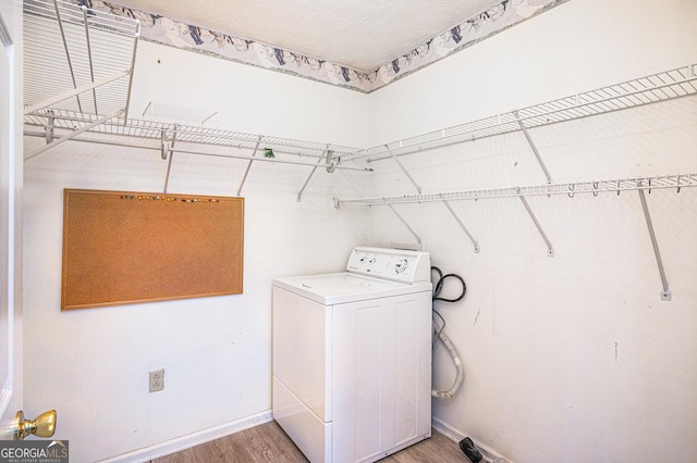 laundry room featuring laundry area, washer / clothes dryer, wood finished floors, and baseboards