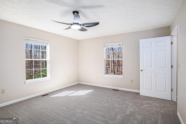 carpeted empty room with visible vents, baseboards, ceiling fan, and a textured ceiling