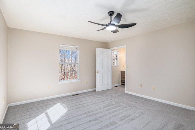 unfurnished bedroom with a textured ceiling, light colored carpet, visible vents, and baseboards