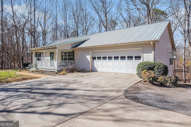 ranch-style home featuring covered porch, an attached garage, a standing seam roof, metal roof, and driveway