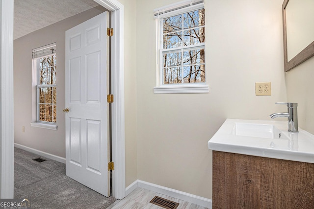 bathroom featuring visible vents, vanity, baseboards, and a textured ceiling