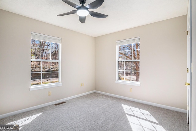 unfurnished room with baseboards, light colored carpet, visible vents, and a healthy amount of sunlight