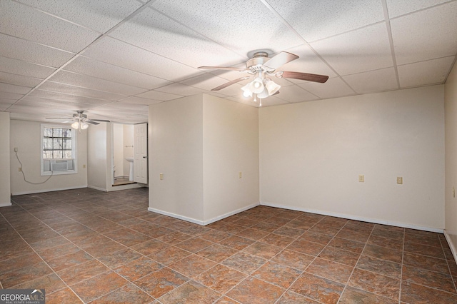 empty room featuring a drop ceiling, cooling unit, a ceiling fan, and baseboards