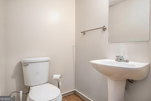 bathroom with toilet, baseboards, and wood finished floors