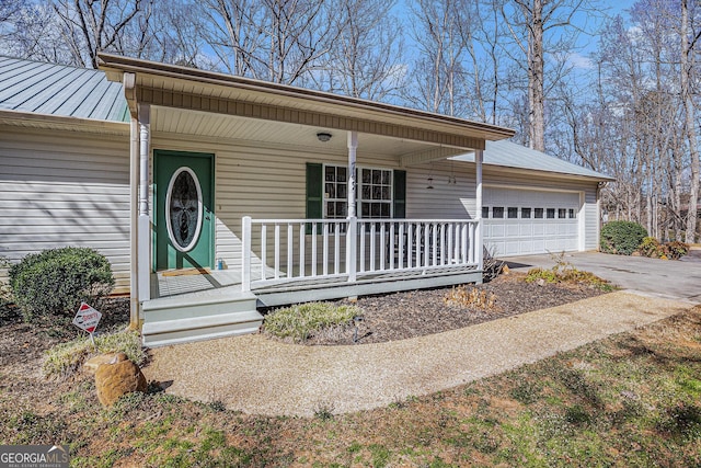 view of front of home with covered porch, a standing seam roof, metal roof, a garage, and driveway