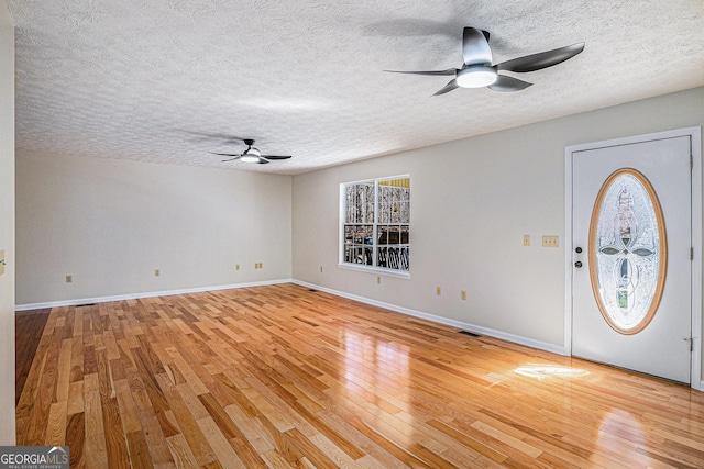 foyer entrance with ceiling fan, light wood-style flooring, baseboards, and a textured ceiling