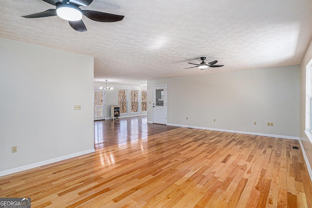 unfurnished living room featuring a textured ceiling, baseboards, and wood finished floors