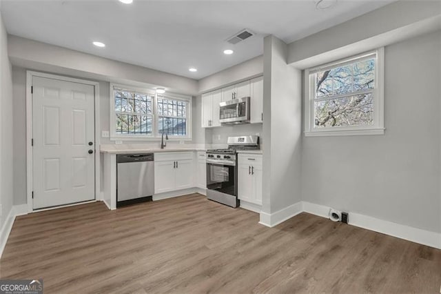 kitchen featuring wood finished floors, visible vents, white cabinetry, light countertops, and appliances with stainless steel finishes