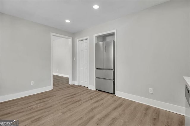 unfurnished bedroom with baseboards, recessed lighting, freestanding refrigerator, and light wood-style floors