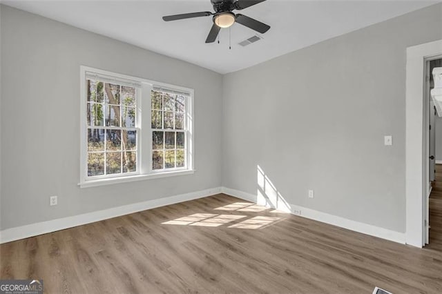 unfurnished room with a ceiling fan, visible vents, baseboards, and wood finished floors