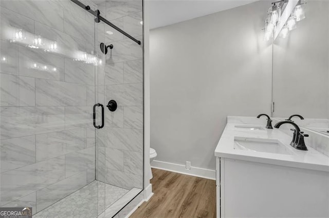 full bath with double vanity, wood finished floors, a sink, and baseboards