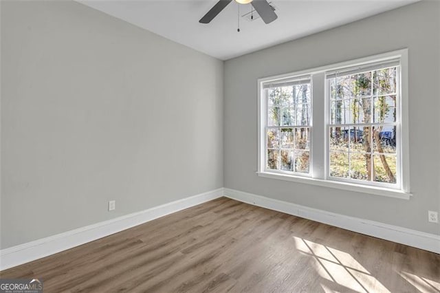 spare room featuring ceiling fan, baseboards, and wood finished floors