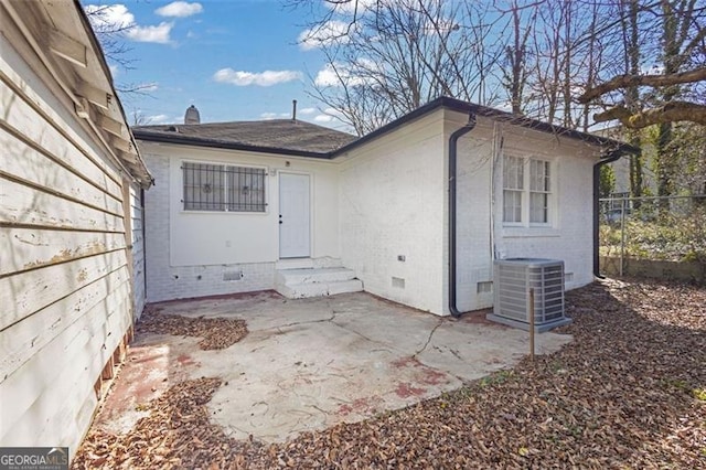 entrance to property featuring brick siding, a patio, central AC unit, crawl space, and fence