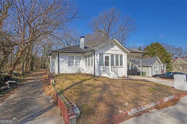 bungalow with concrete driveway and a chimney