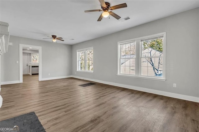 unfurnished living room with baseboards, visible vents, and wood finished floors