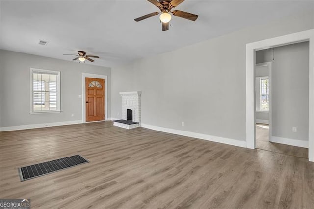 unfurnished living room with plenty of natural light, visible vents, a fireplace, and baseboards