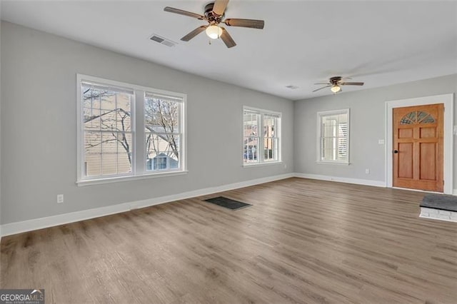 unfurnished living room featuring baseboards, visible vents, ceiling fan, and wood finished floors