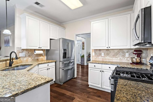 kitchen featuring appliances with stainless steel finishes, white cabinetry, a sink, and hanging light fixtures