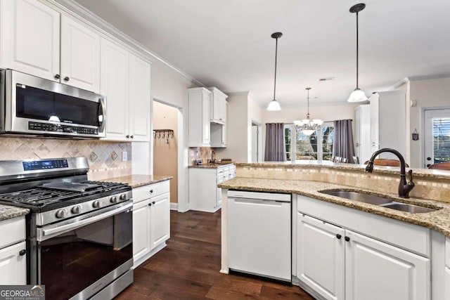 kitchen with appliances with stainless steel finishes, a sink, white cabinetry, and decorative light fixtures