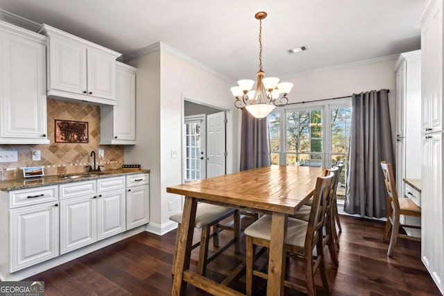 dining area with crown molding, visible vents, dark wood finished floors, and a notable chandelier