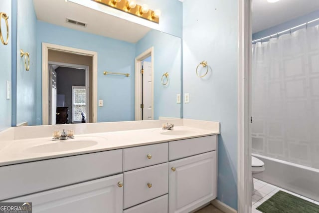 bathroom with visible vents, double vanity, a sink, and toilet