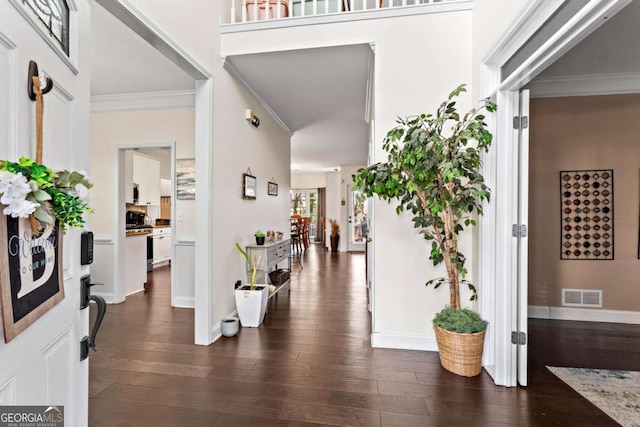 entrance foyer with baseboards, visible vents, dark wood-type flooring, and crown molding