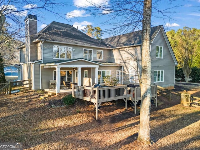 rear view of house featuring a chimney and a wooden deck