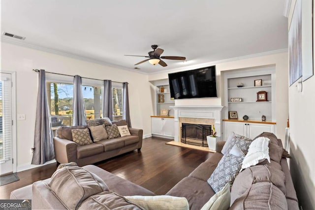 living room featuring visible vents, dark wood-style floors, ceiling fan, ornamental molding, and a fireplace