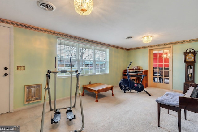 exercise room with heating unit, visible vents, and light colored carpet