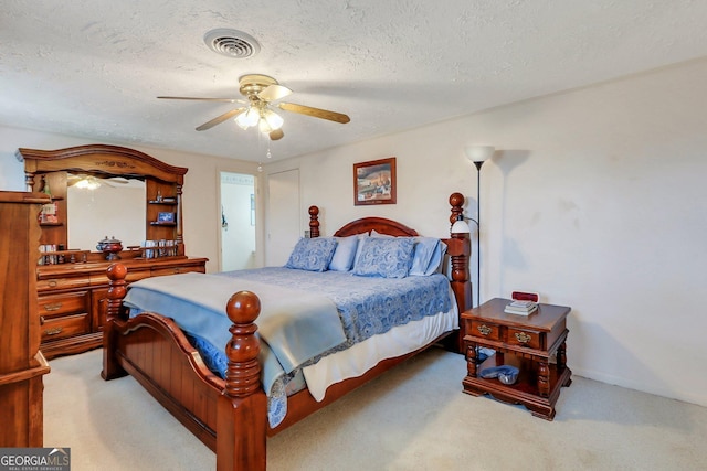 bedroom featuring ceiling fan, visible vents, a textured ceiling, and light colored carpet