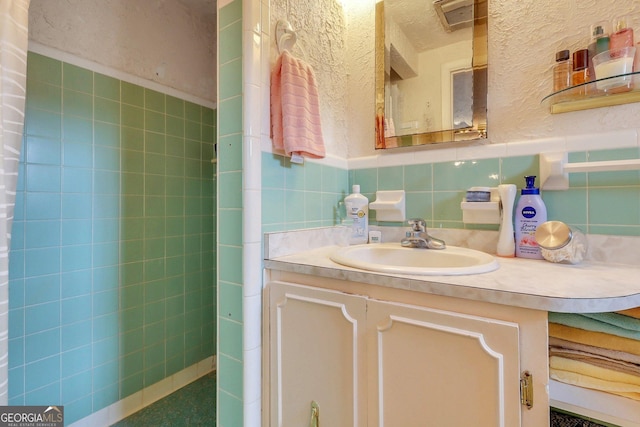 bathroom featuring a textured wall, wainscoting, tile walls, and vanity