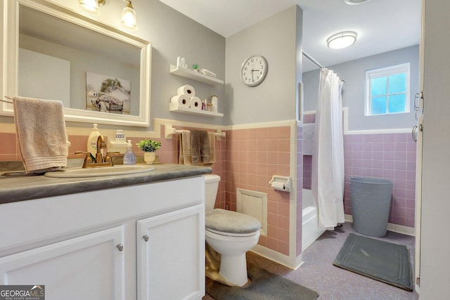 full bathroom with toilet, vanity, tile walls, and wainscoting