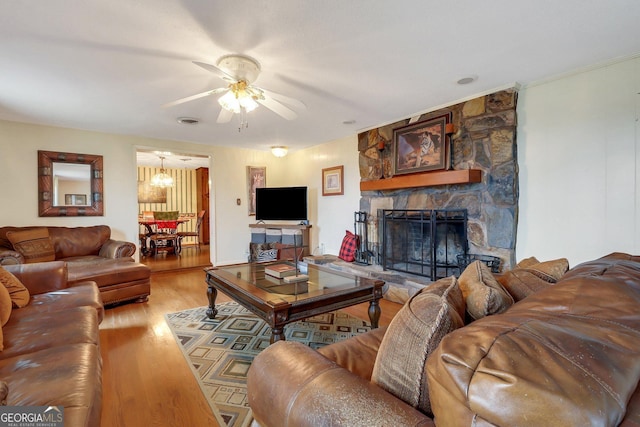 living area featuring ceiling fan, a fireplace, wood finished floors, and visible vents