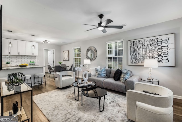 living area with wood finished floors, a ceiling fan, and baseboards