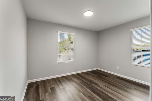 spare room featuring dark wood-style flooring and baseboards