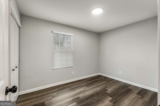 unfurnished bedroom featuring dark wood-type flooring, a closet, and baseboards