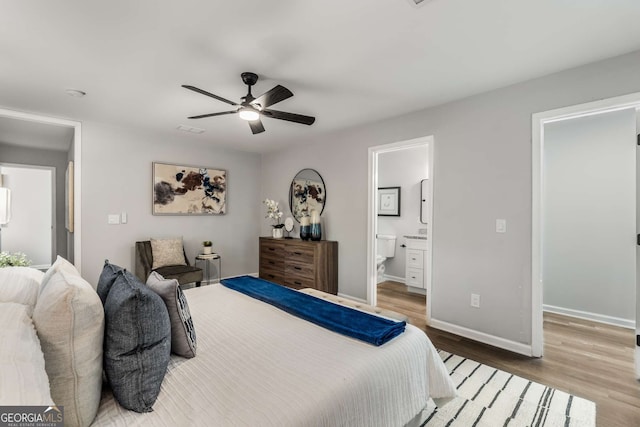 bedroom featuring visible vents, ensuite bathroom, a ceiling fan, wood finished floors, and baseboards