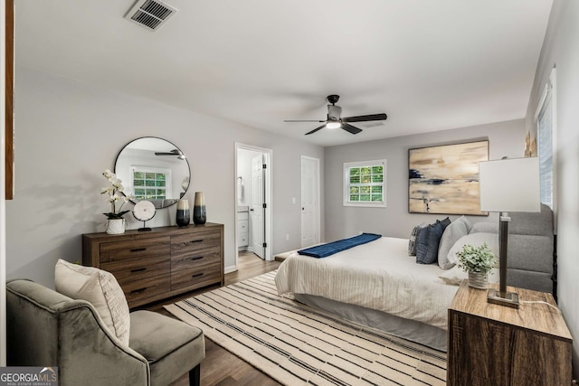 bedroom with visible vents, ceiling fan, connected bathroom, wood finished floors, and baseboards