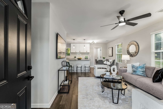 living area with baseboards, dark wood finished floors, and a ceiling fan