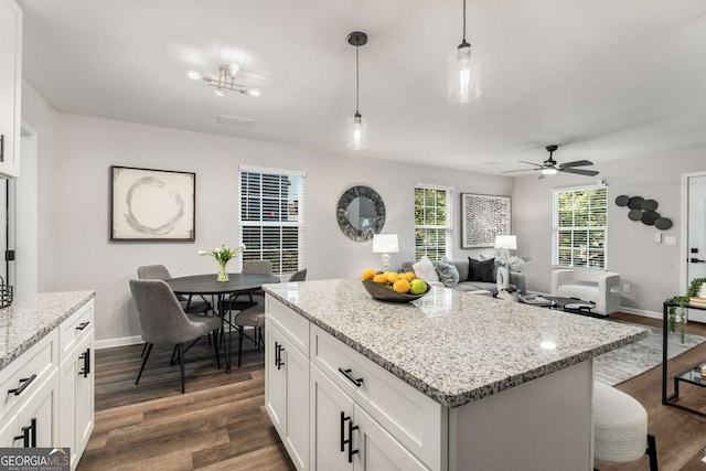 kitchen featuring dark wood-style flooring, a center island, white cabinetry, and pendant lighting