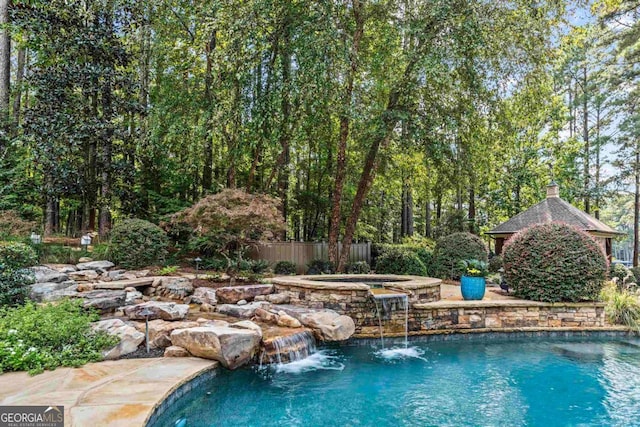 outdoor pool featuring fence and an in ground hot tub