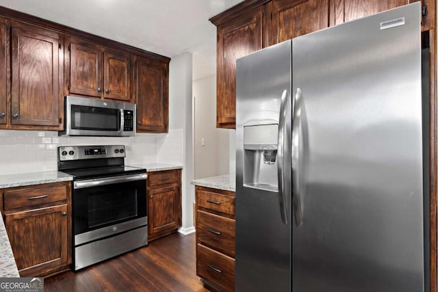 kitchen featuring tasteful backsplash, stainless steel appliances, dark wood-type flooring, and light stone countertops