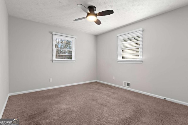 spare room featuring a wealth of natural light, baseboards, visible vents, and carpet flooring