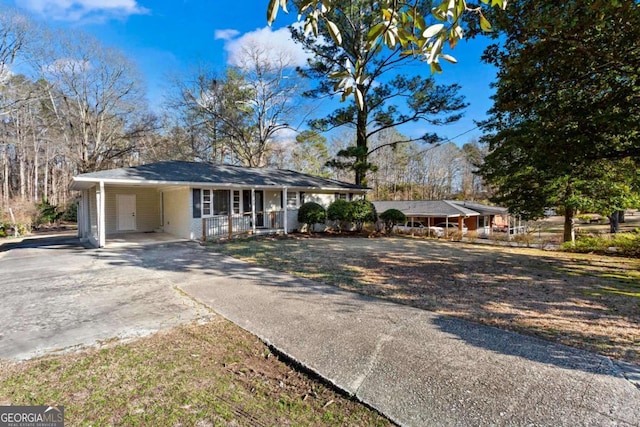 ranch-style home with concrete driveway, a carport, a porch, and brick siding