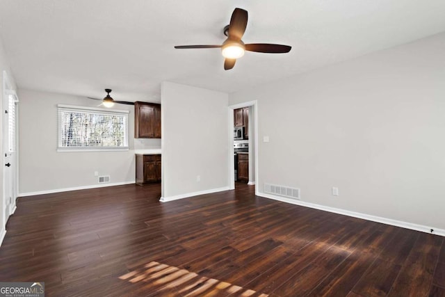 unfurnished living room featuring visible vents, dark wood finished floors, and baseboards