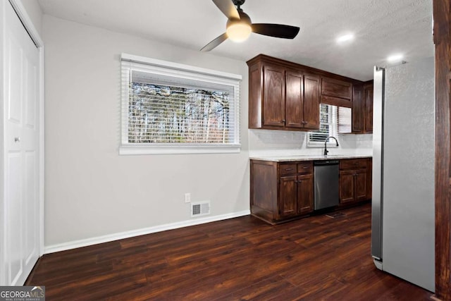 kitchen featuring dark brown cabinetry, stainless steel appliances, dark wood-type flooring, visible vents, and light countertops